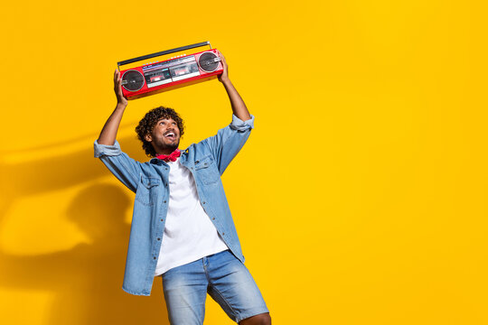 Photo portrait of nice young male raise look boombox rap music dressed stylish denim outfit red scarf isolated on yellow color background
