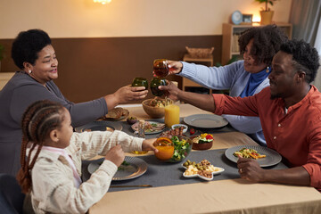 Portrait of three generation African American family enjoying dinner together in cozy home and...