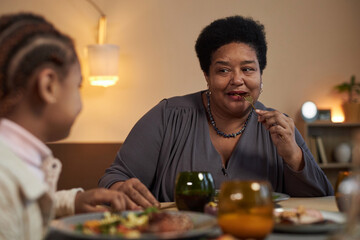 Portrait of African American senior woman enjoying dinner with family sitting at table together and...