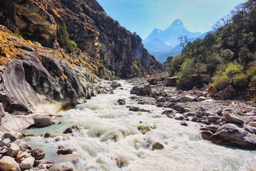Scenic view of Ama Dablam rising from the mists in the deep valleys of the Dudh kosi river in Nepal - obrazy, fototapety, plakaty