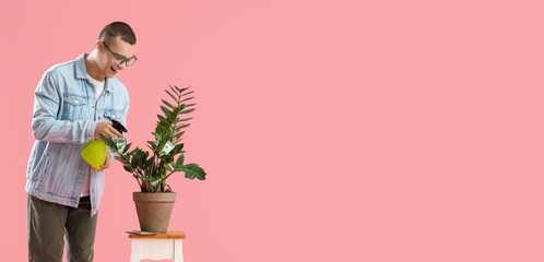 Young man watering plant with money on pink background with space for text. Concept of business...