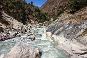 Fast moving rapids of the Dudh Kosi river originating from the Khumbu and Cho Oyu glaciers seen here in a scenic valley setting on the Everest Base Camp trek near Tengboche,Nepal - obrazy, fototapety, plakaty