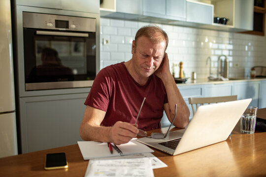 Stressed man going over bills at home