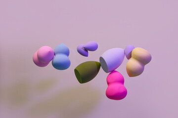 Flying different makeup sponges on purple background
