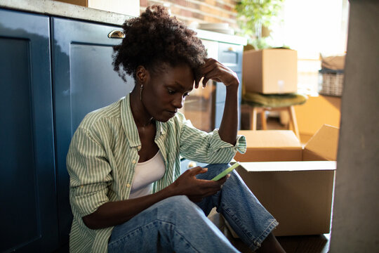 Woman using smartphone on floor with moving boxes around