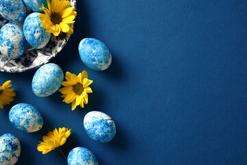 Happy Easter greeting card. Colorful Easter eggs with yellow flowers on dark blue background.