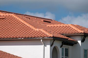 Overlapping rows of yellow ceramic roofing tiles covering residential building roof in southern...