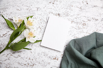 White blank card on a distressed white painted surface, accompanied by Alstroemeria flowers and a...