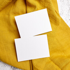 blank white cards presented on a mustard yellow textured fabric backdrop