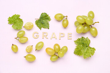 Word GRAPE and fresh green berries with leaves on lilac background