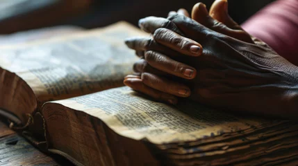 Cercles muraux Vielles portes Person's hands folded in prayer over an open, well-worn bible, resting on a wooden table