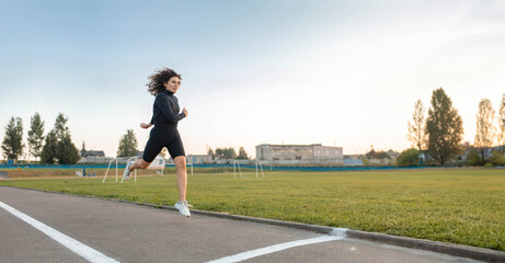 young woman jogging at the stadium. Curly-haired sportswoman jogging in the morning.