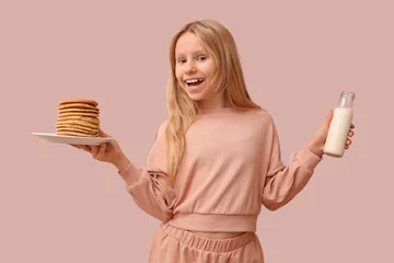  Little girl with tasty pancakes and bottle of milk on beige background © Pixel-Shot