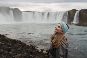 Traveling and exploring Iceland landscapes and travel destinations. Young female tourist enjoying the view and outdoor spectacular scenery. Summer tourism by Atlantic ocean and mountains.