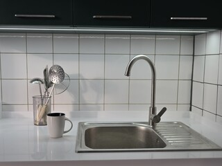 White countertop and sink with dishes in a kitchen decorated with white tiles