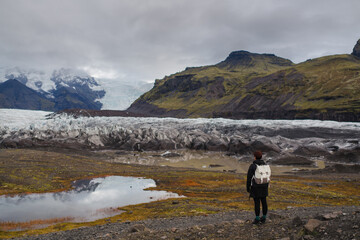 Traveling and exploring Iceland landscapes and travel destinations. Young female tourist enjoying the view and outdoor spectacular scenery. Summer tourism by Atlantic ocean and mountains.