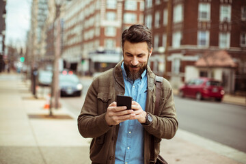 Man drinking coffee and looking at smartphone in city