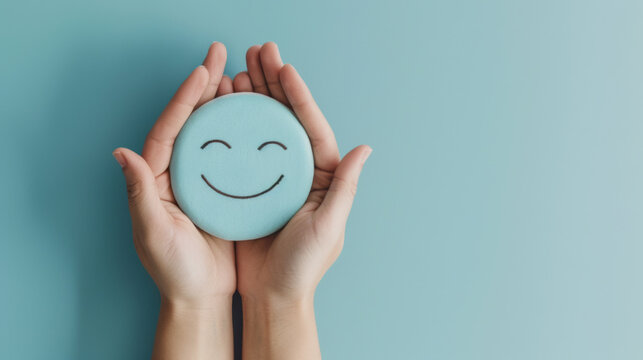 Two hands gently hold a smiling blue sphere against a calming turquoise background, conveying a sense of joy and emotional well-being.