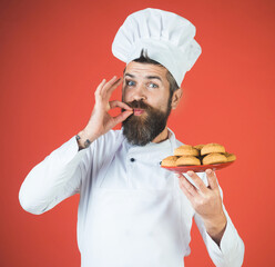 Male chef with plate oatmeal cookies showing ok sign. Smiling chef, cook or baker with taste...