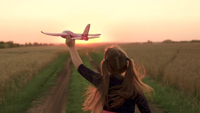 girl plays countryside toy airplane, girl hair flutters wind while running airplane sunset, child holds airplane hand sunset, dreams flying, kid child girl daughter runs with toy airplane hand park.