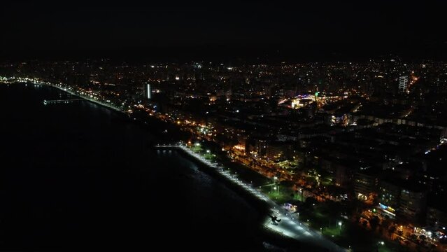 Panoramic drone view of Mersin's city skyline at night. Night aerial footage showing Mersin's illuminated city skyline. Drone captures city skyline of Mersin illuminated at night.