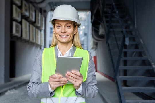 Professional caucasian woman in helmet and neon yellow vest standing at construction with digital tablet in hands. Experienced female architect checking house building process and entering data. - Powered by Adobe