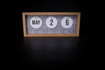 A wooden calendar block showing the date May 26th on a dark black background, save the date or date of an event concept.