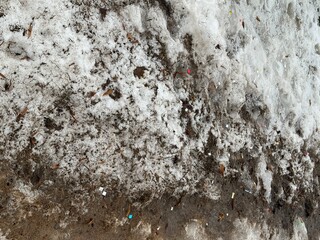 Melting dirty snow on the streets of the city during the daytime in winter. Snow with sand and mud lies on the road