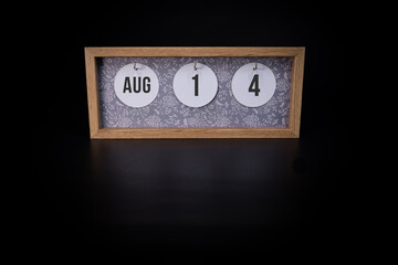 A wooden calendar block showing the date August 14th on a dark black background, save the date or date of event concept