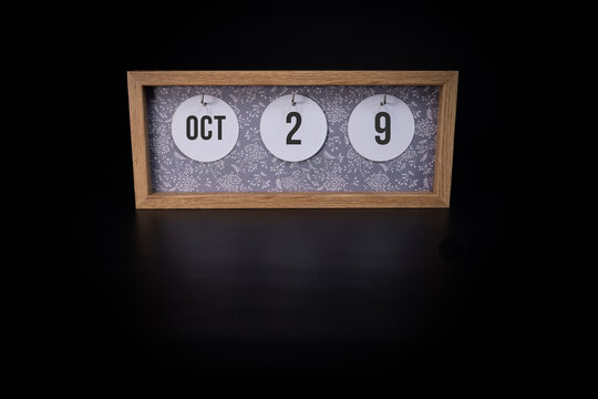 A wooden calendar block showing the date October 29th on a dark black background, save the date or date of event concept