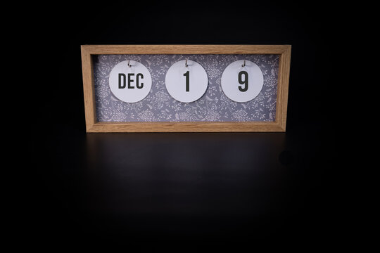 A wooden calendar block showing the date December 19h on a dark black background, save the date or date of event concept