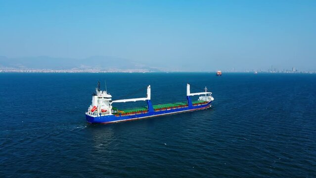 Bulk cargo carrier ship for carrying dry cargo cruising across the sea to commercial port. Aerial view