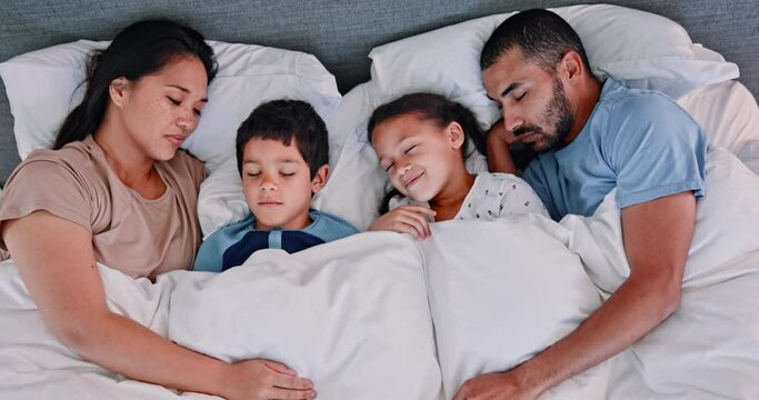 Happy family, sleeping and relax with cuddle on bed for comfort, rest or weekend together above at home. Top view of mother, father and children asleep under duvet sheets or comforter in bedroom