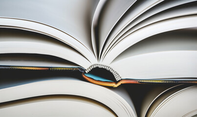 Open book with pages fanned out creating an abstract pattern. Macro shot with focus on texture of paper. Reading and knowledge concept. Design for poster, educational material, book-themed wallpaper.