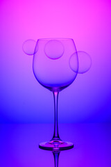 wine glass with soap bubbles on blue and pink background 1
