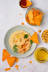 Plate with hummus, chips, olive oil, paprika, herbs. Traditional oriental snack. View from above.