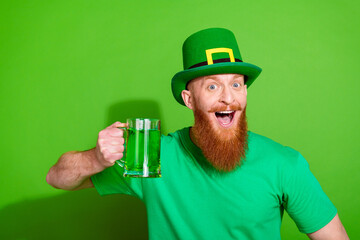 Photo of overjoyed handsome guy have fun hand hold ginger ale mug isolated on green color background