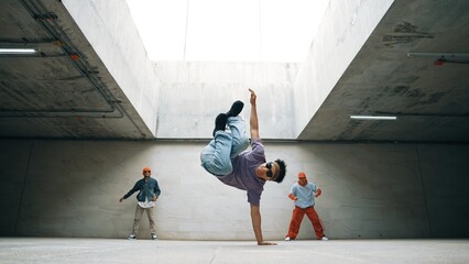 Group of stylish hipster perform dancing together in building. Happy break dancer enjoy moving to...