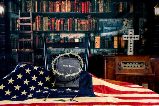 Bible and crown of thorns on American flag with rose head nails in old library