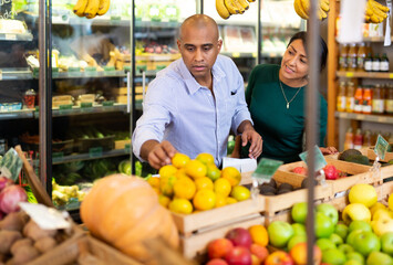 Married couple choosing fruits in grocery store