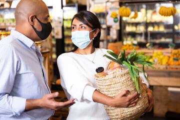 Family couple in protective mask choosing groceries together in supermarket