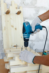Master cabinetmaker makes wooden furniture with drill, nails, hammer. Handmade in home workshop.