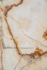 Close up view of marble surface with shades of yellow and brown intricate patterns formed by veins of mineral deposits. White and grey tones creating elegant appearance