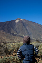 Naklejka premium Young traveler. Boy of 4 years old looks at volcano Teide in front of him.