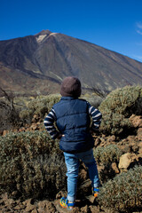 Naklejka premium Young traveler. Boy of 4 years old looks at volcano Teide in front of him.
