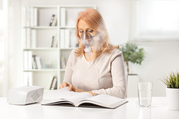 Woman reading a book and using a nebulizer at home