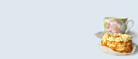 A sweet treat on a light monochrome background. Next to the dessert, in the background is a faded colorful vintage teacup and saucer. Sweet surprise, gift concept. Minimalism. Food and drink