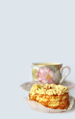 A sweet treat on a light monochrome background. Next to the dessert, in the background is a faded colorful vintage teacup and saucer. Sweet surprise, gift concept. Minimalism. Food and drink