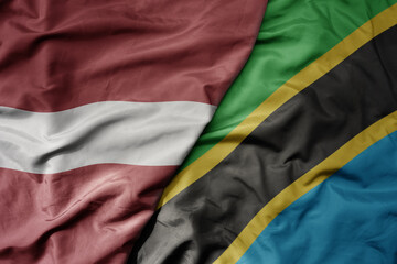 big waving national colorful flag of tanzania and national flag of latvia.