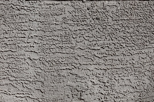 Decorative dark lace and skip coarse sand stucco finish applied to external wall, background or photographic backdrop, closeup